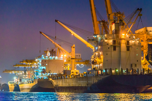 Container Cargo freight ship with working crane bridge in shipyard