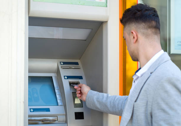 istock young man insert credit card to atm 667075436
