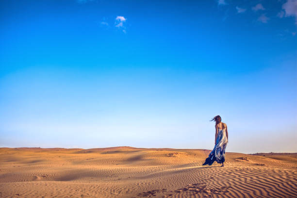 istock slim girl standing in the sand dunes 667075644