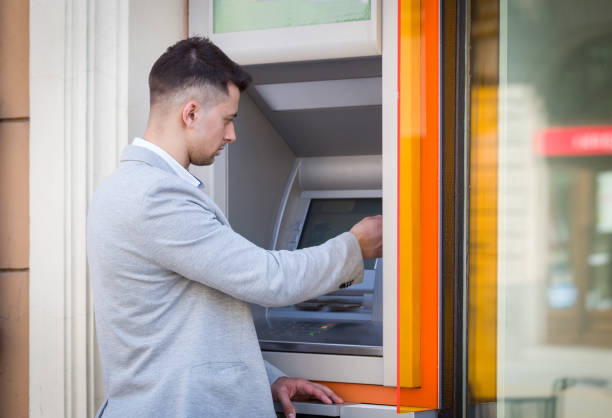 istock young man insert credit card to atm 667075760