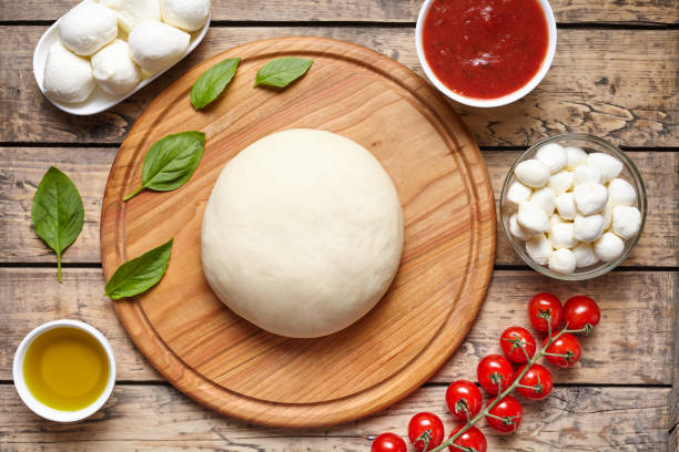 istock Pizza cooking ingredients. Dough, mozzarella, tomatoes, basil, olive oil, spices. Work with the dough. Top view. Flat lay. Traditional italian pizza margherita. 667078848