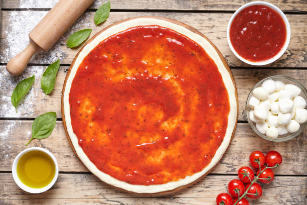 istock Raw dough for pizza with ingredient: tomato sauce, mozzarella, tomatoes, basil, olive oil, cheese, spices served on rustic wooden table. Flat lay. Italian pizza margarita 667079158