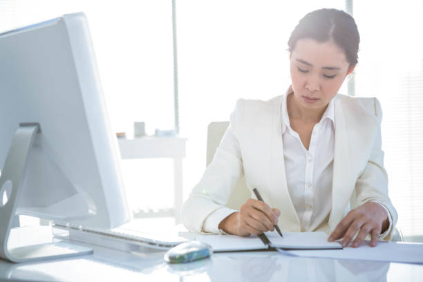 istock Businesswoman writing on diary on desk 667084220
