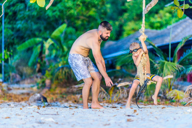 istock Riding on the bungee, tropical pattern - dad helping his son to get on it 667090336