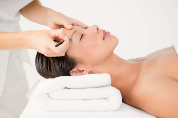 istock Woman using tweezers on patient eyebrow 667104218