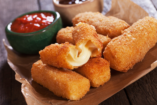 Breaded mozzarellla cheese sticks with ketchup and bbq sauce