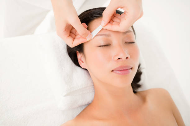 Hand waxing beautiful womans eyebrow Close up view of hands waxing beautiful womans eyebrow asian eyebrows stock pictures, royalty-free photos & images