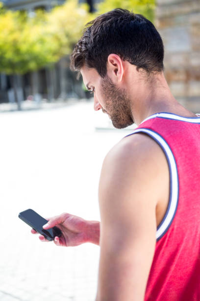 istock Rear view of an handsome athlete sending a text 667115146