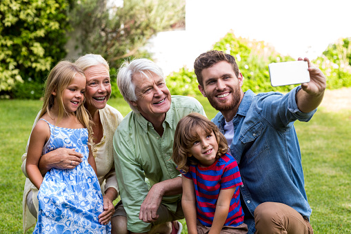 Happy father taking selfie with family while sitting in yard
