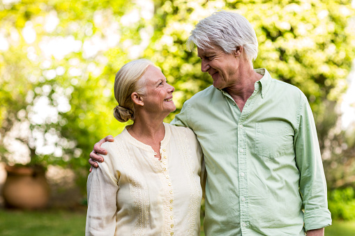Smiling senior couple looking each other while standing in yard