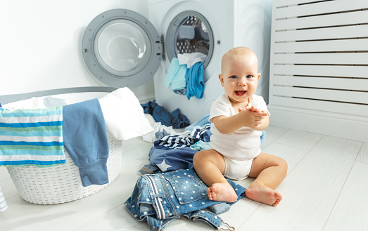 divertido feliz bebé para lavar ropa y risas en lavandería photo