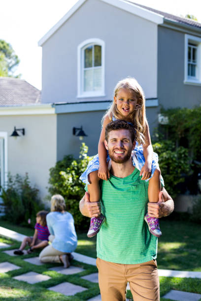 istock Smiling father carry daughter on shoulders in yard 667139722