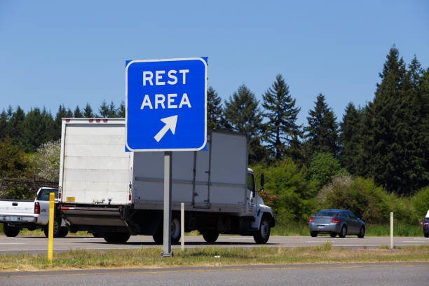 Interstate 5, Oregon - May 7, 2015: Blue rest area sign point to a public exit off the highway with vehicles passing by in the background.