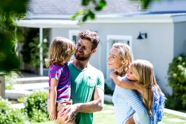 istock Parent carrying children in yard 667141160