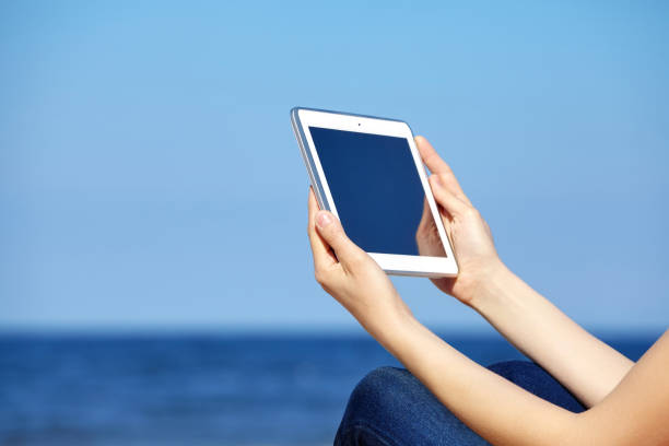 istock Close up of female hands with tablet computer on a beach. 667148518