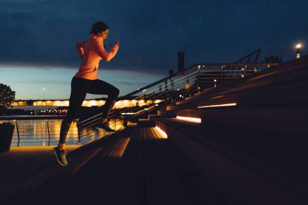 young woman jogging at night on riverside - night running imagens e fotografias de stock
