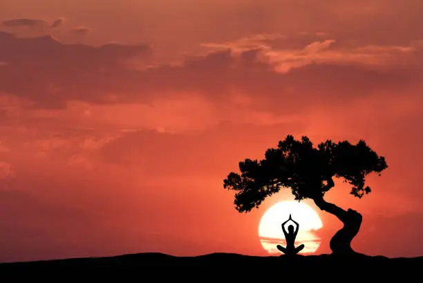 Photo of Silhouette of a sitting woman practicing yoga