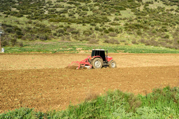 istock Farmer with tractor seeding crops at field 667162638