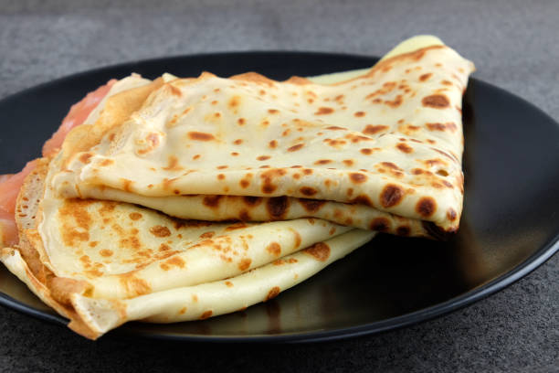 istock Two pancakes with salmon and cheese on black plate. 667188768