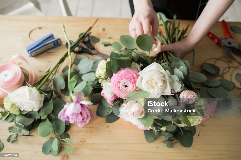 Fleuriste au travail : jolie jeune femme faisant le bouquet moderne fashion de différentes fleurs - Photo de Composition florale libre de droits