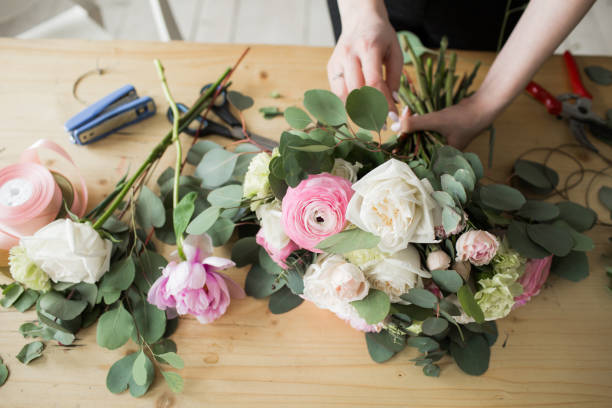 Florist at work: pretty young woman making fashion modern bouquet of different flowers Florist at work: pretty young woman making fashion modern bouquet of different flowers. flower arrangement stock pictures, royalty-free photos & images