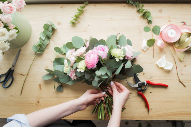 florist at work: pretty young woman making fashion modern bouquet of different flowers - flower arrangement flower bouquet arrangement imagens e fotografias de stock