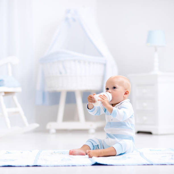 istock Baby boy drinking milk in sunny nursery 667207672