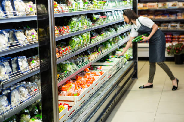 Portrait of a smiling worker taking a vegetables Portrait of a smiling worker taking a vegetables in supermarket produce section stock pictures, royalty-free photos & images