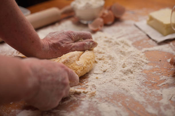 istock Senior woman hands knead dough on table in  home kitchen 667214732