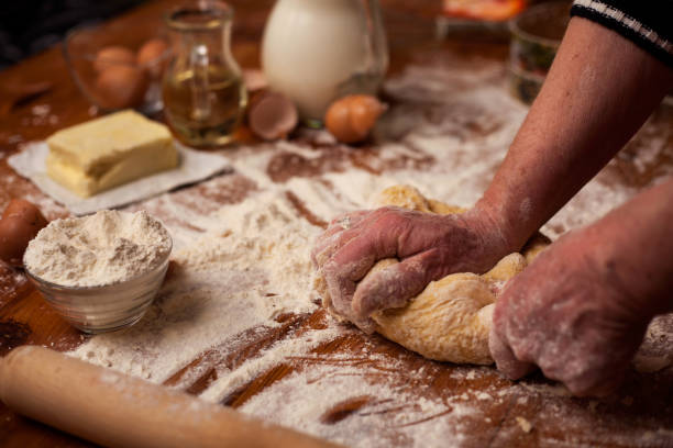 istock Senior woman hands knead dough on  table in  home kitchen 667217426