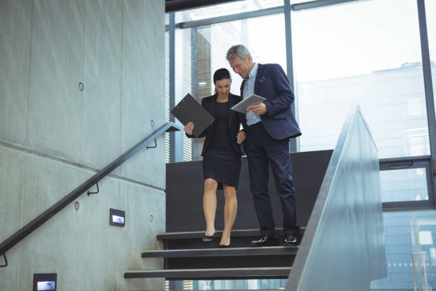 istock Business executives discussing over digital tablet on stairs 667217632