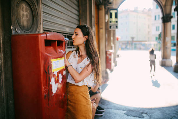 portrait of a young brunette in trieste, italy writing a postcard - writing letter correspondence women imagens e fotografias de stock