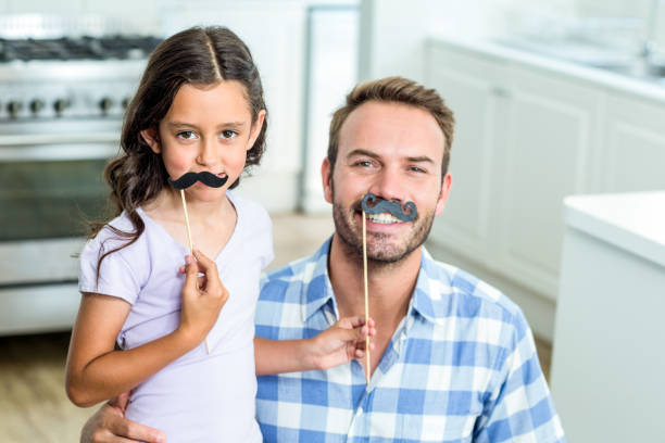 istock Father and daughter with artificial mustache at home 667218264