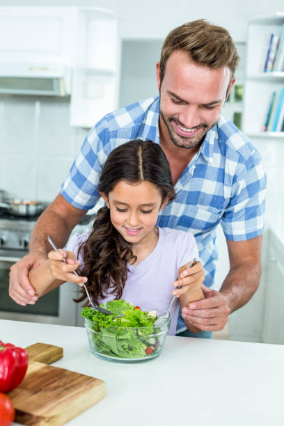istock Father assisting daughter in preparing salad 667218476