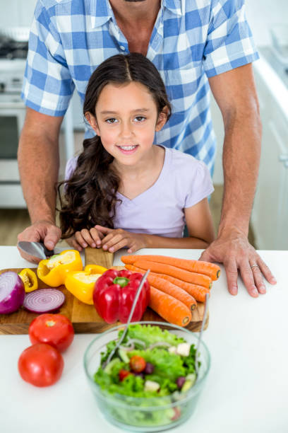 istock Daughter with father by vegetables at kitchen table 667218510