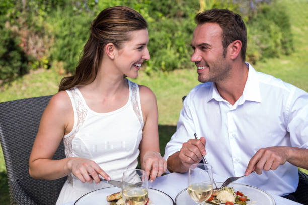Smiling young couple having meal while sitting on chairs at park