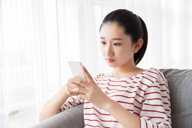 istock Young woman playing with smart phone at home 667245376