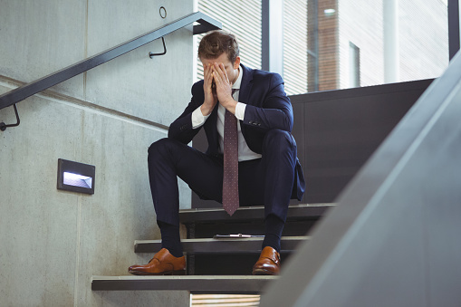 Depressed businessman sitting on stairs at office