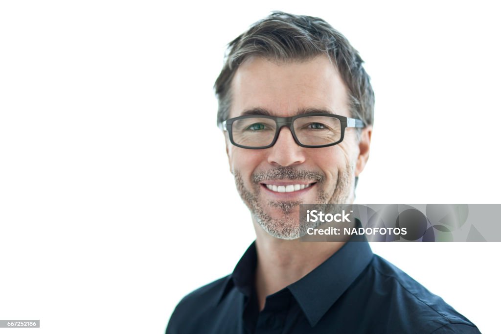 Portrait Of A Handsome Man Smiling At The Camera. Isolated On White. With Glasses. men, 50-59 years, mature men, smiling, isolated on white, healthy lifestyle, senior adult, attractive male, human face, tranquil scene, males, 40-49 years, success, portrait, male beauty, leadership, sales occupation, beard, fashion model, one person, casual clothing, adult, close-up, caucasian ethnicity, cool, confidence, indoors, copy space, brown hair, elegance, lifestyles, head and shoulders, positive emotion, glamour, human hair, satisfaction, aspirations, energy, joy, content, looking at camera, attitude, masculinity, green eyes, 50s, glasses Men Stock Photo