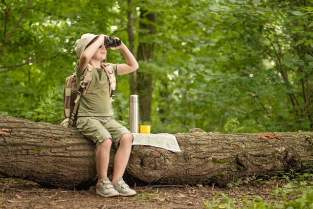 girl looking at birds through binoculars, camping in the woods