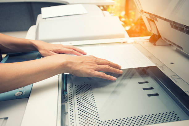 woman hands putting a sheet of paper into a copying device - ladder company 1 imagens e fotografias de stock