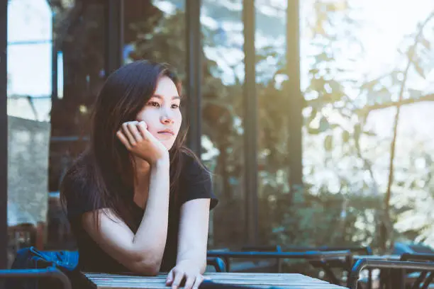 Photo of Asia youth teenager sitting depression on chair. Lifestyle people concept in cafe.