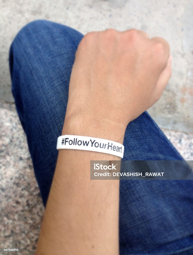 White wristband in wrist, hand on blue jeans. Blue Jeans, Wristband, White, Fist, Hand Bracelet Stock Photo