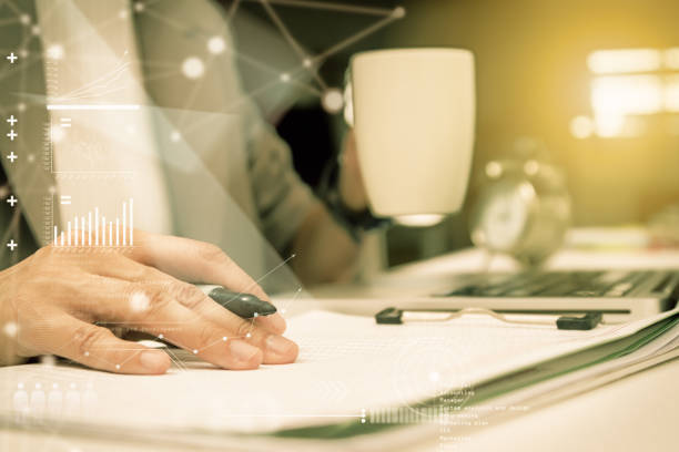 istock Using computer in office with a cup of coffee,Young woman working on a laptop computer while enjoying a cup of tea or coffee, close up side view of the notebook,business people,business background,business content and film effect. 667270764