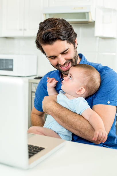 istock Man sitting with son by laptop at table 667271506