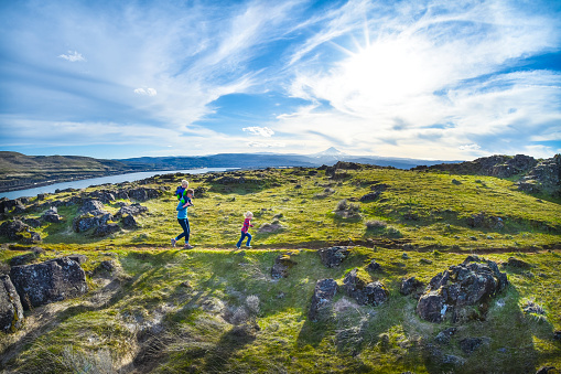 A mother and her two young children hike through a meadow at Horsethief Butte in Columbia Hills State Park, Washington State. Mt. Hood, the Columbia River, and The Dalles, Oregon are in the background.