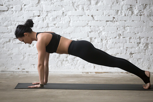 Joven yogui atractiva mujer en la pose de Plank, Fondo de Loft blanco photo