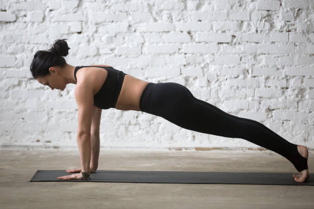 joven yogui atractiva mujer en la pose de plank, fondo de loft blanco - good posture yogaclass lifestyles sport fotografías e imágenes de stock