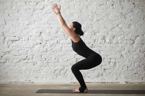 mujer atractiva joven yogui utkatasana postura, blanco fondo de loft - good posture yogaclass lifestyles sport fotografías e imágenes de stock