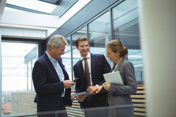 istock Businesspeople discussing over electronic devices in the passageway 667296344